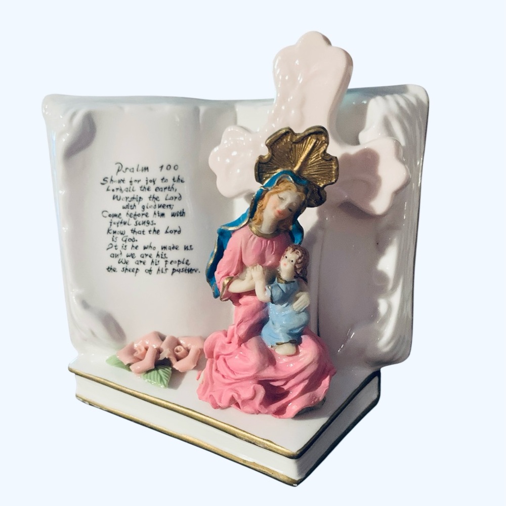 Vintage figurine Virgin Mary and child, set against an open book and a cross.